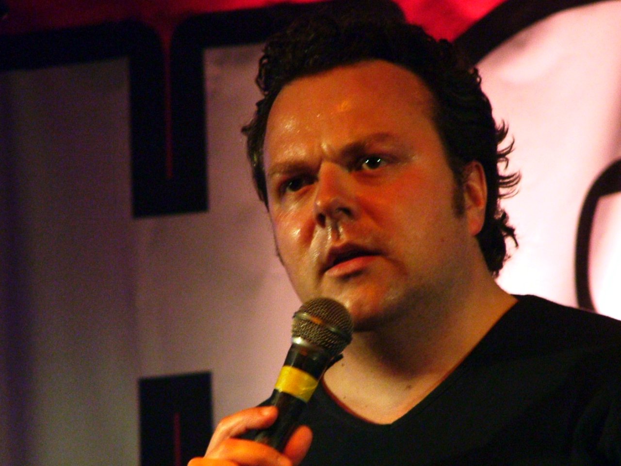 Comedian Hal Cruttenden performing on stage.